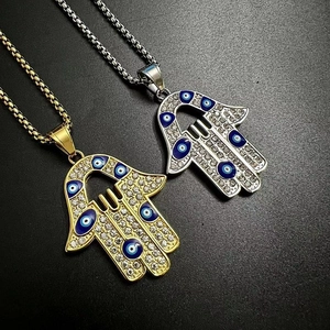 Vue détaillée des pendentifs main de Fatma en or et argent avec zircons et œil bleu