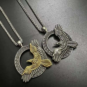 Dettaglio dei ciondoli corvo di Odino vichingo in acciaio argento e oro con nodi