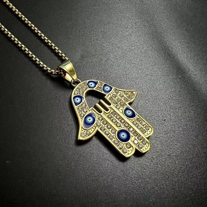 Détail du pendentif Main de Fatima dorée avec yeux bleus et strass scintillants