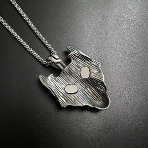 Macro detail of Nordic Viking wolf head pendant with green eyes and textured silver finish