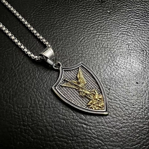 Macro shot of St. Michael shield pendant with gold angel relief on black leather
