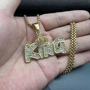Close-up of gold-plated KING crown pendant with shimmering cubic zirconia on box chain