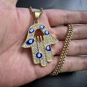 Détail du pendentif Main de Fatma dorée avec motifs œil bleu et strass étincelants