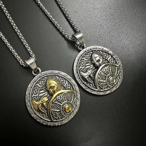 Détails de deux pendentifs bouclier viking en tons argent et or sur un fond gris mat