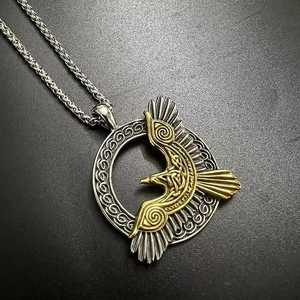 Dettaglio del ciondolo corvo vichingo di Odino con finiture dorate e nodi d'argento