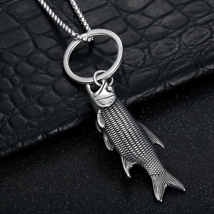 Vintage stainless steel fish bottle opener keychain with textured scales on dark background