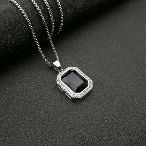Detalle de cadena de caja plateada con colgante rectangular negro y circonitas