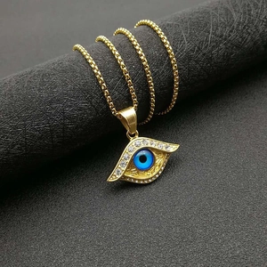 Detailaufnahme des vergoldeten Titananhängers Böser Blick mit blauer Perle und Kristallen