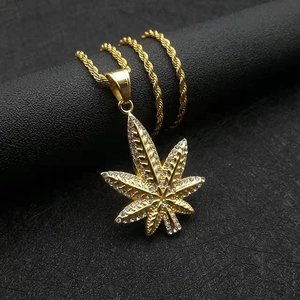 Vue macro du pendentif feuille de cannabis plaqué or avec strass sur une chaîne corde