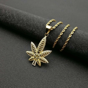 Détail macro du pendentif feuille d'érable plaqué or avec zircons sur une chaîne corde
