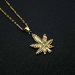 Gros plan du pendentif feuille d'érable plaqué or avec strass et chaîne de corde torsadée