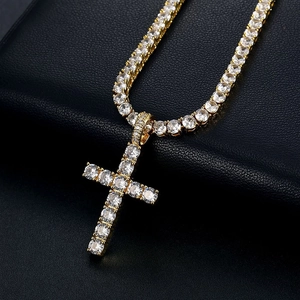 Macro shot of hip hop cross pendant with iced out stones on a gold tennis chain