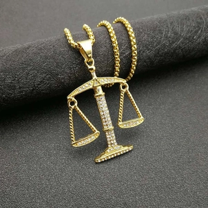 Gold-plated Libra zodiac pendant necklace with sparkling cubic zirconia on stone background