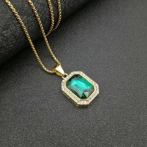Detalle de un collar bañado en oro con gema verde corte esmeralda y halo de circonitas