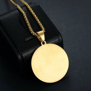 Close-up of golden stainless steel round pendant with box chain on black leather jewelry box