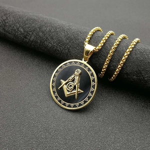 Detailed close-up of golden Freemasonry AG emblem pendant with black matte finish and chain