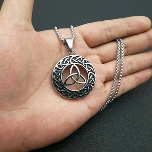 Detail of silver Celtic Triquetra knot pendant with box chain on a dark textured background