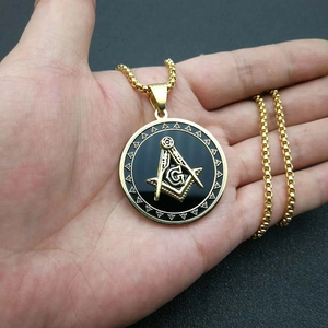 Close-up of golden Freemasonry pendant with square and compass on a hand-held chain