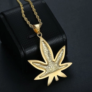 Macro detail of gold maple leaf pendant with textured grains on black leather display
