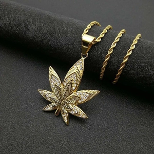 Macro shot of gold plated hemp leaf pendant with micro-paved rhinestones on twist chain