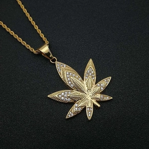 Macro view of gold plated maple leaf pendant with pavé cubic zirconia on twisted rope chain
