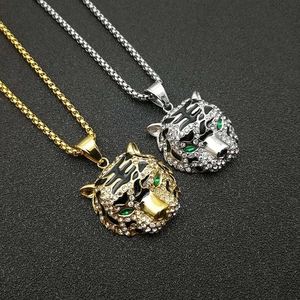 Gros plan de pendentifs tête de tigre en or et argent avec strass brillants et yeux verts