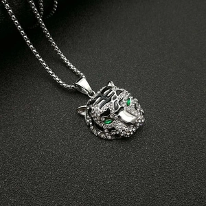 Détail macro du pendentif tête de tigre serti de cristaux et yeux en gemmes vertes