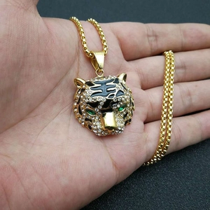 Détail du pendentif tête de tigre doré orné de cristaux blancs et yeux verts