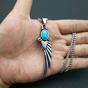 Retro titanium steel feather wing necklace with oval turquoise stone held in hand