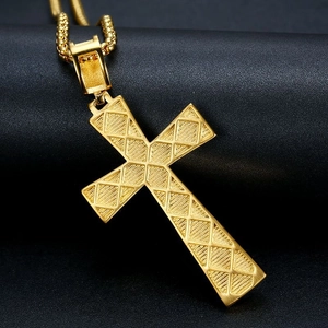 Pendentif croix en acier titane doré avec chaîne vénitienne sur un fond noir texturé