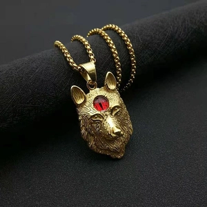 Détail macro du pendentif tête de loup viking doré avec œil rouge sur socle noir