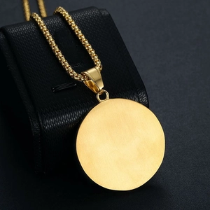 Detail of a polished gold-plated round pendant with a sturdy box chain on a black stand