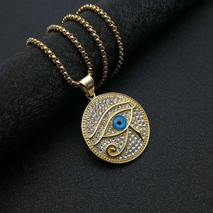Makroaufnahme des vergoldeten Horusauge-Anhängers mit Strass und blauem Zentrum