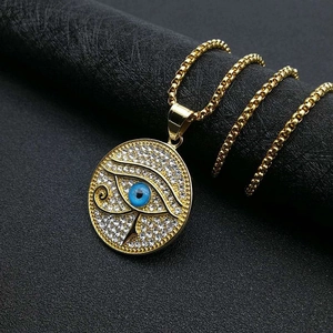 Makroaufnahme des vergoldeten Horusauge-Anhängers mit funkelnden Kristallen und blauem Detail
