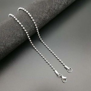 Detailed view of silver stainless steel ball chain with lobster clasp on black background