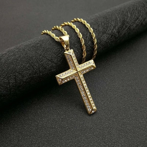 Détail d'un pendentif croix plaqué or serti de cristaux sur une chaîne de corde