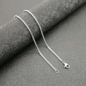 Polished silver stainless steel box chain necklace with lobster clasp on display stand