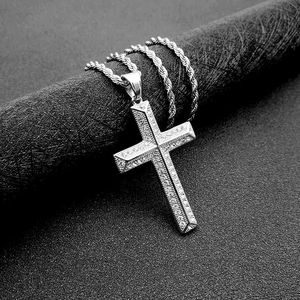 Détail d'un pendentif croix en acier titane argenté avec cristaux et chaîne cordelette