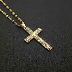 Détail macro du pendentif croix en acier titane doré avec zircons et sa chaîne torsadée