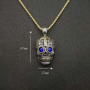 Collier tête de mort punk vintage en acier inoxydable doré avec des yeux bleus ornés