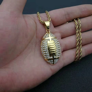 Macro-opname van goudkleurige rugby hanger met kristallen en kruis aan een gedraaide ketting