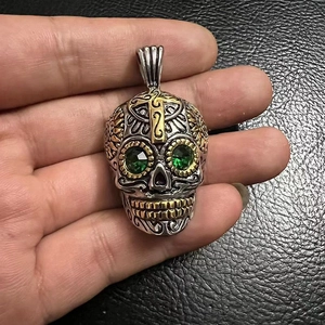 Détail d'un pendentif crâne punk avec des yeux en pierres vertes et des touches dorées