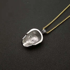 Détail du pendentif crâne bicolore avec finition argentée et chaîne à mailles carrées dorée