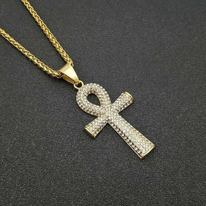 Gros plan du pendentif clé Ankh doré avec strass sur un collier à chaîne tressée