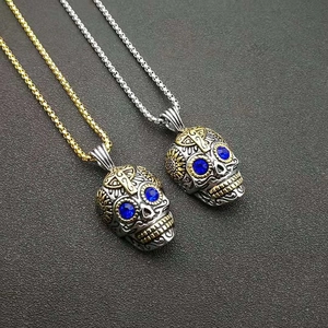 Détail d'un pendentif tête de mort punk avec yeux bleus et gravures dorées vintage