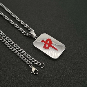 Silberne kubanische Halskette mit rotem Mahjong Anhänger auf grauem Stein Hintergrund