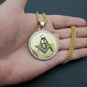 Macro shot of gold-plated Freemason pendant with zircon stones and brick wall texture