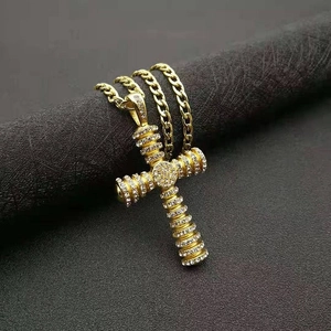 Macro detail of gold cross pendant with white pavé zircons and cuban link chain