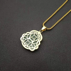 Detail of gold-plated Buddha pendant with green resin stone and filigree metal patterns