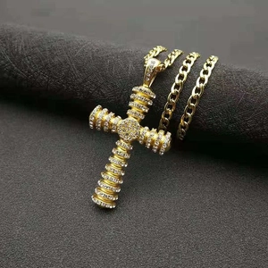 Macro detail of gold-plated iced out cross pendant with cubic zirconia on cuban chain